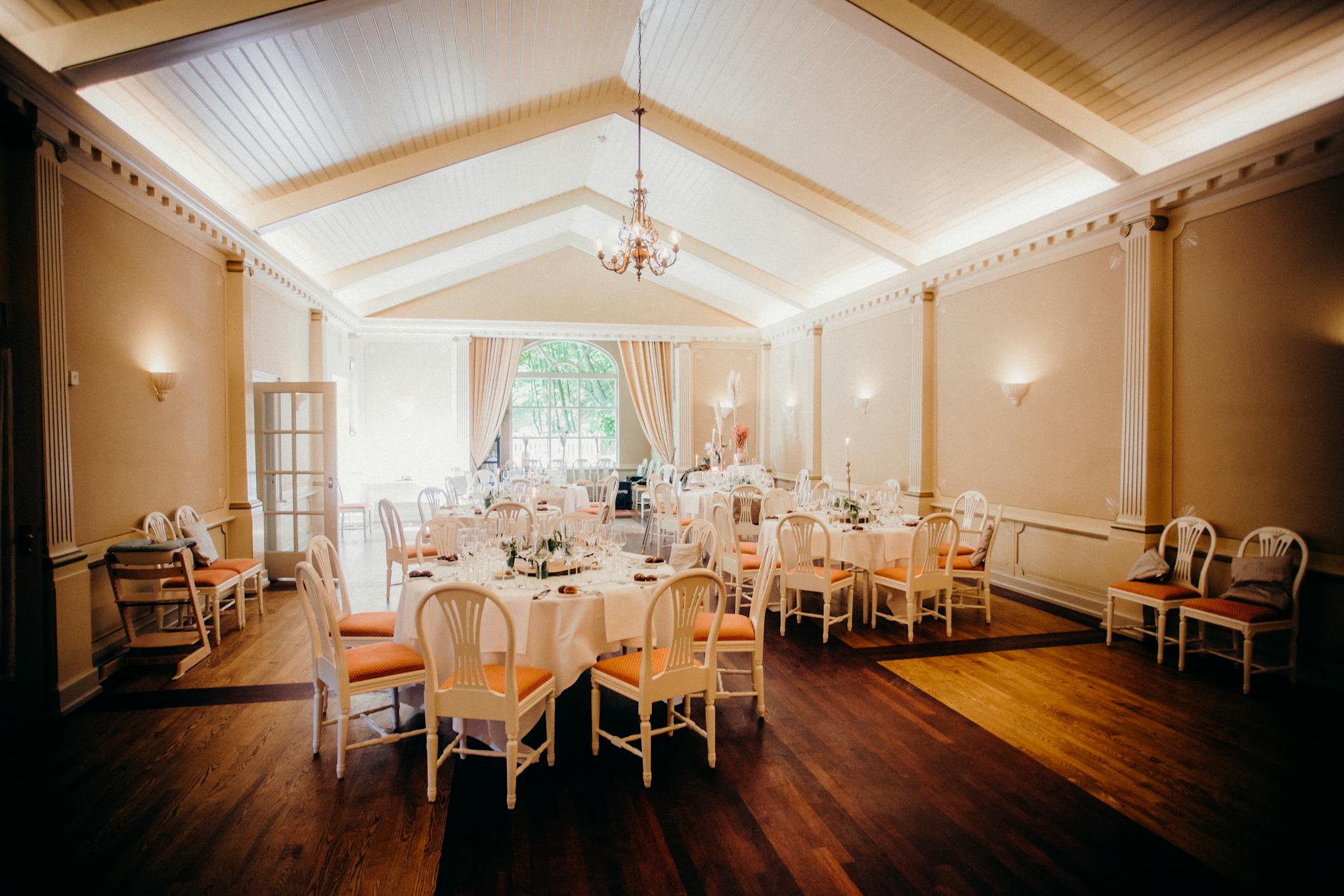 Elegancka sala weselna z udekorowanymi stołami i ciepłym oświetleniem