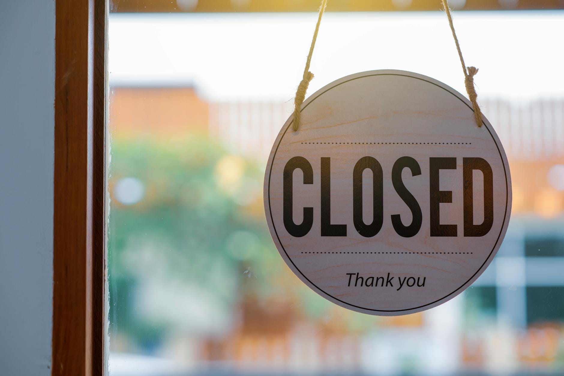 Drewniana tabliczka closed na szybie sklepu w czasie zamknięcia biznesu