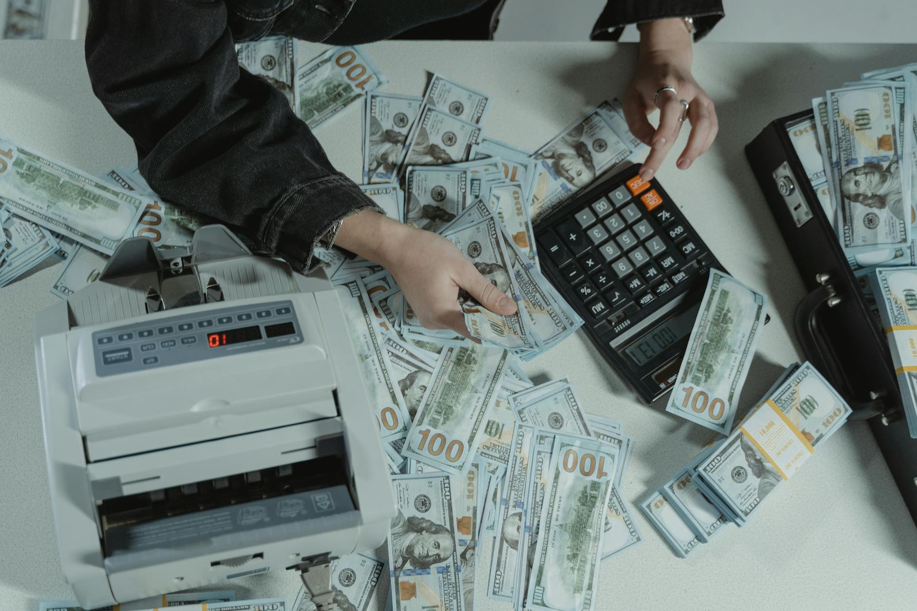 Płynność finansowa czy zyskowność co ważniejsze dla przedsiębiorcy Ręce liczące setki dolarów przy kalkulatorze na biurku