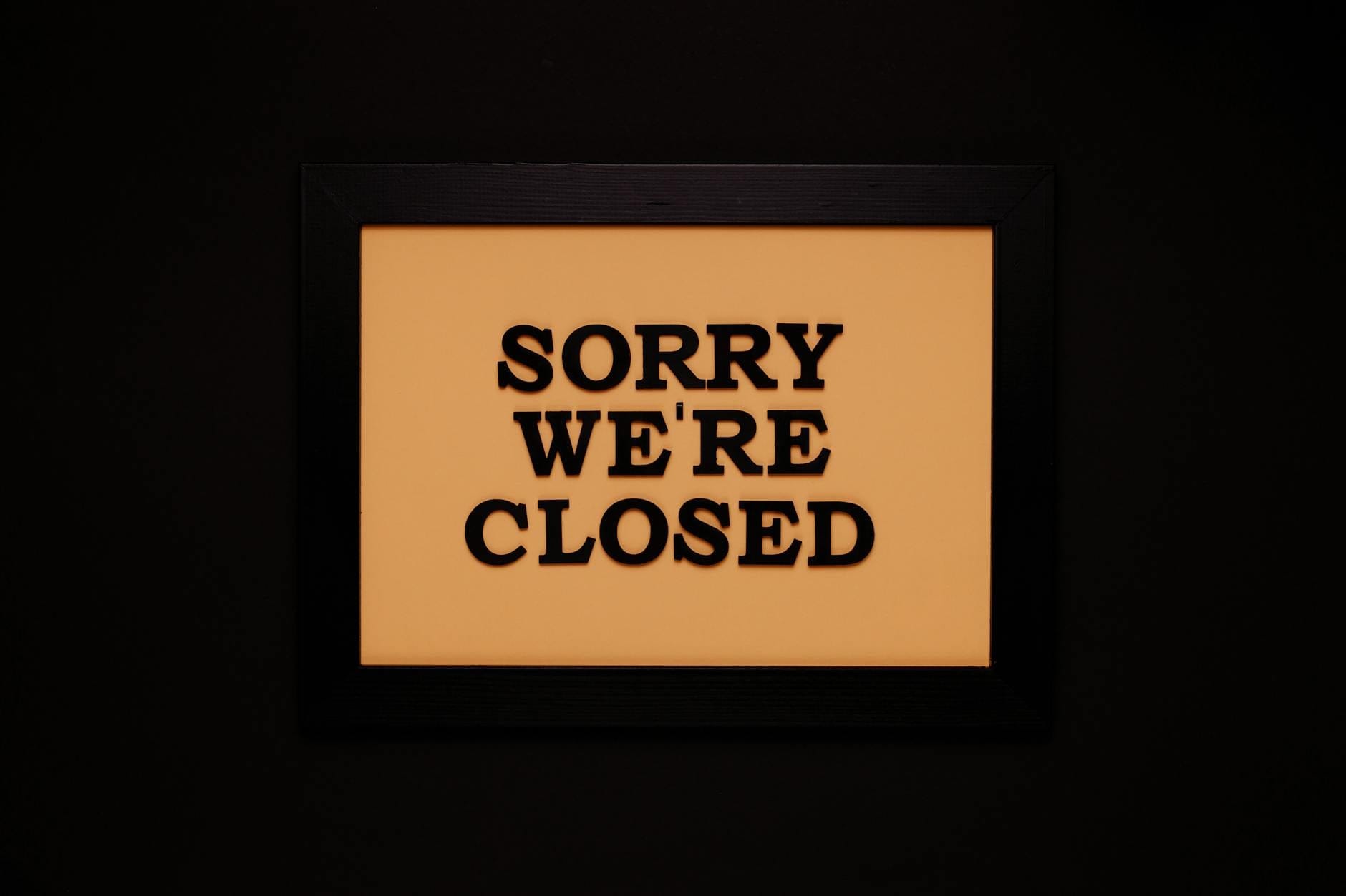 Kiedy restrukturyzacja nie ma sensu: sygnały, że lepiej kontrolowanie zakończyć działalność Tabliczka Sorry We’re Closed na ciemnym tle w zamkniętym lokalu