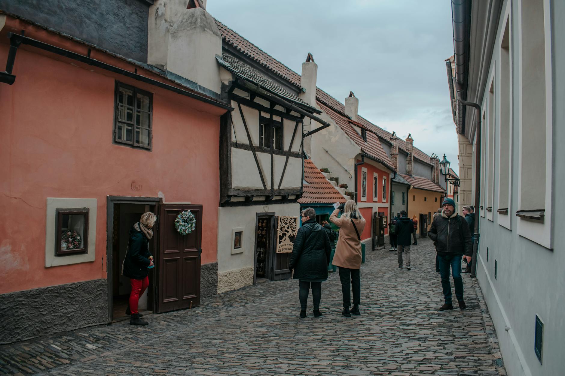 Turyści spacerują Złotą Uliczką w Pradze między kolorowymi kamienicami