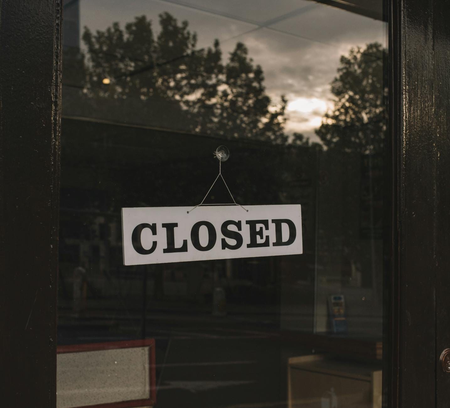 Zamknięty lokal usługowy z białą tabliczką Closed na szybie