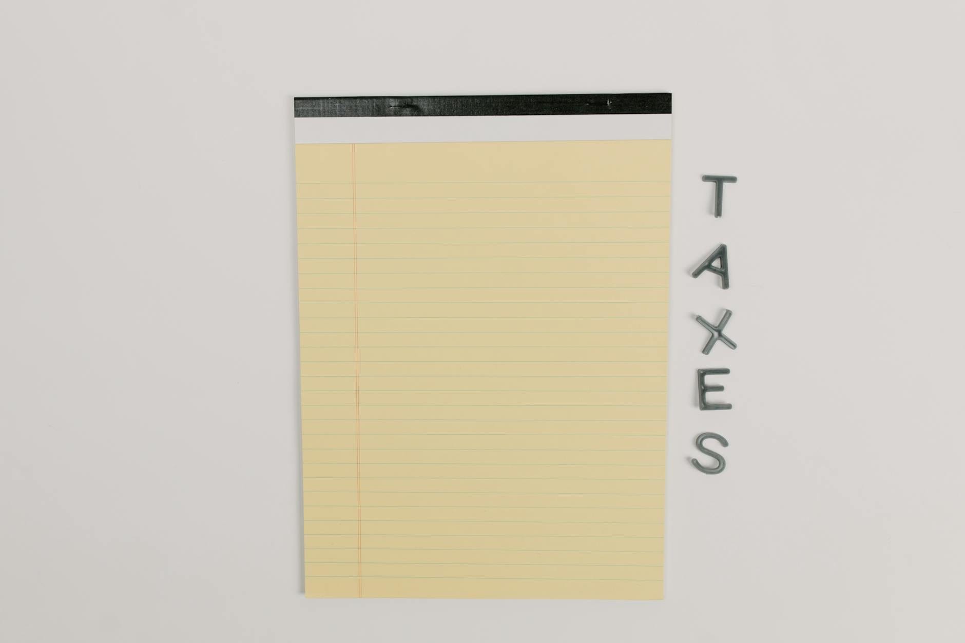 Notatnik prawniczy obok napisu TAXES na białym biurku