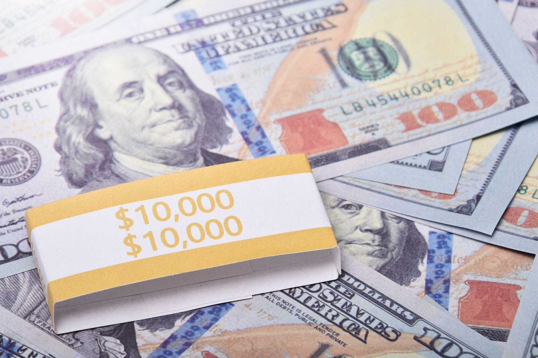 Zastaw, hipoteka, przewłaszczenie: które zabezpieczenia najlepiej chronią majątek firmy w praktyce Plik banknotów 100 dolarów spięty banderolą 10 000 jako majątek firmy